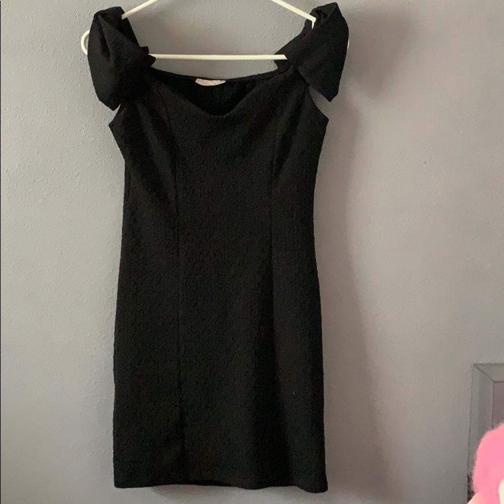 A black small dress with ruffles on the shoulders.